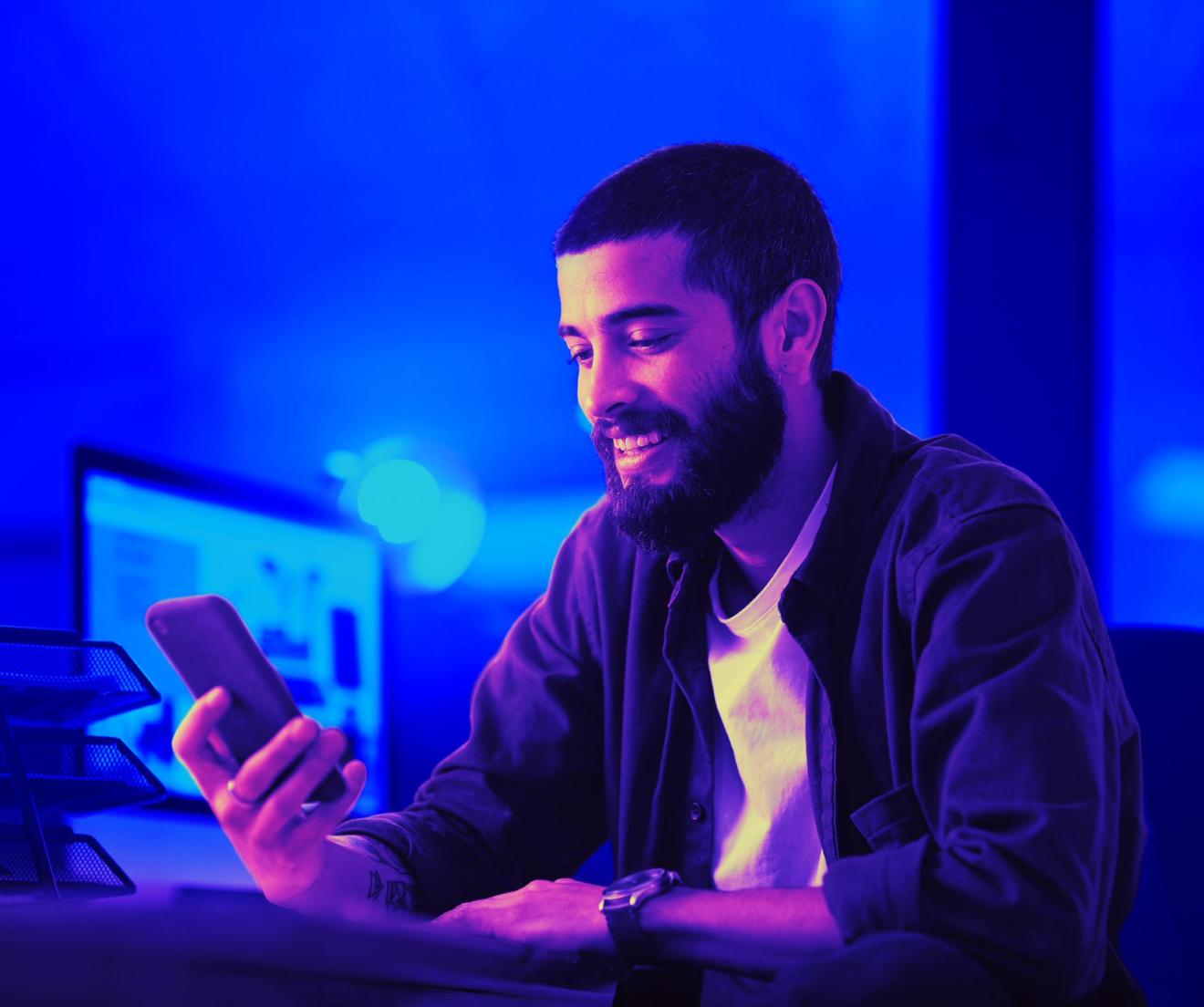 man smiling while using his smartphone