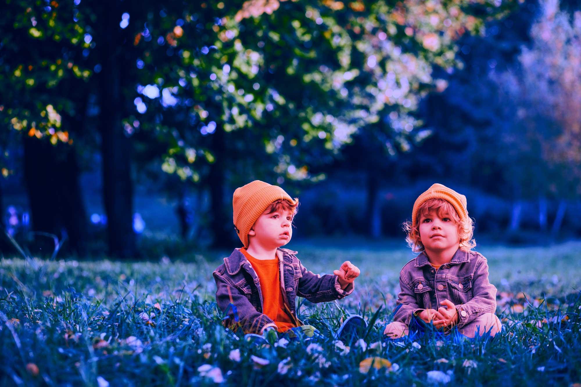 young twins sitting on a field of grass